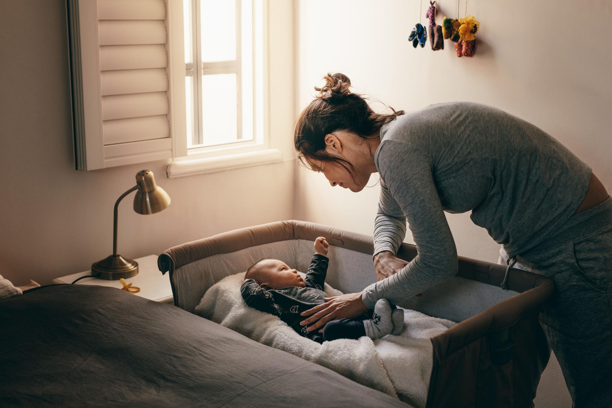  A crib placed in a softly lit room, surrounded by gentle decor and a warm atmosphere.