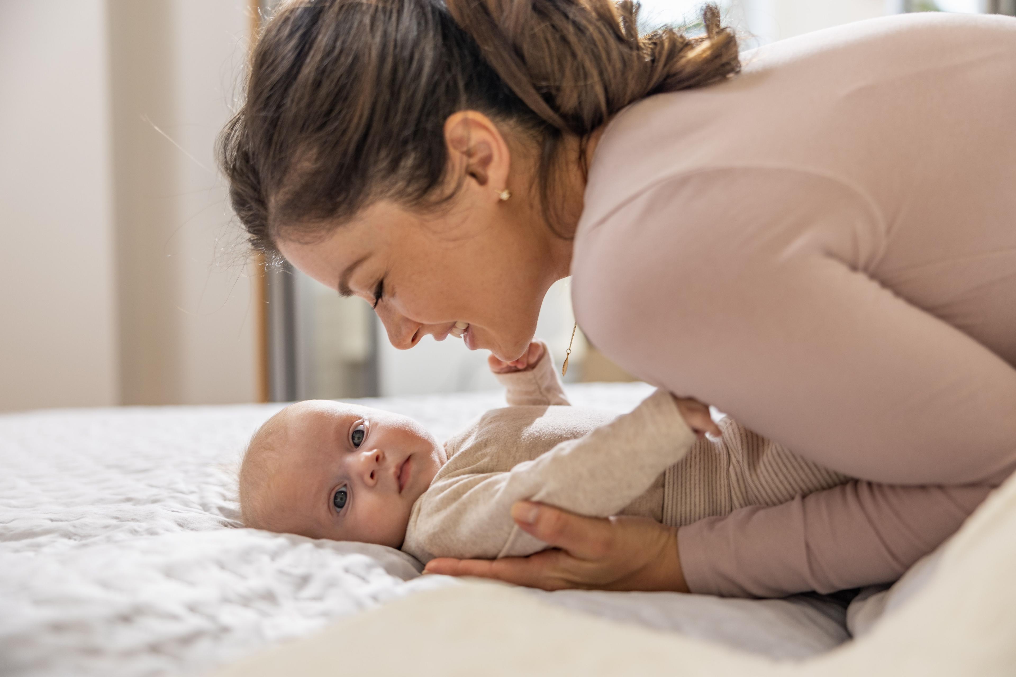 Young mom plays with her newborn baby